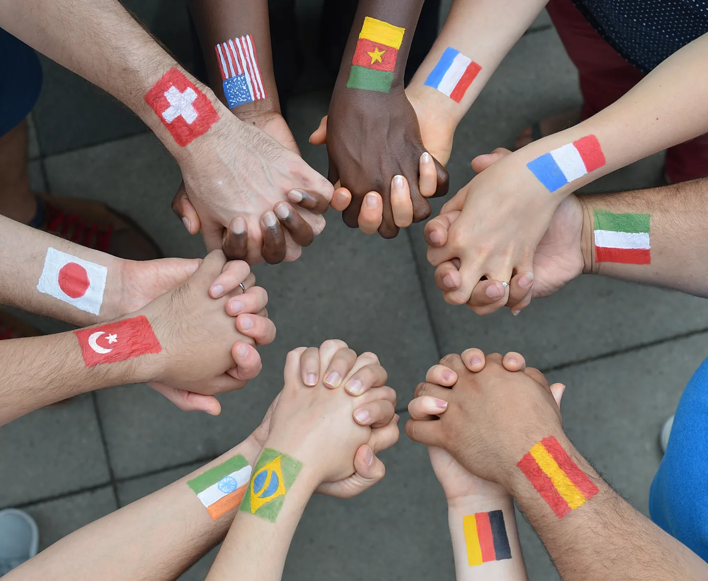 Hands holding flags from around the world — clients from Canada, USA, Europe, Asia, and Latin America